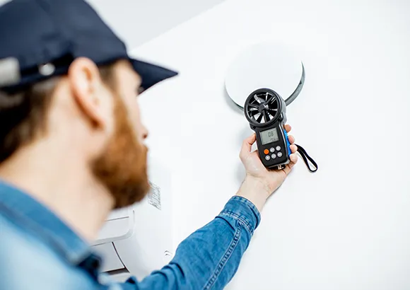 Hand holding an air quality monitoring device in a home setting.