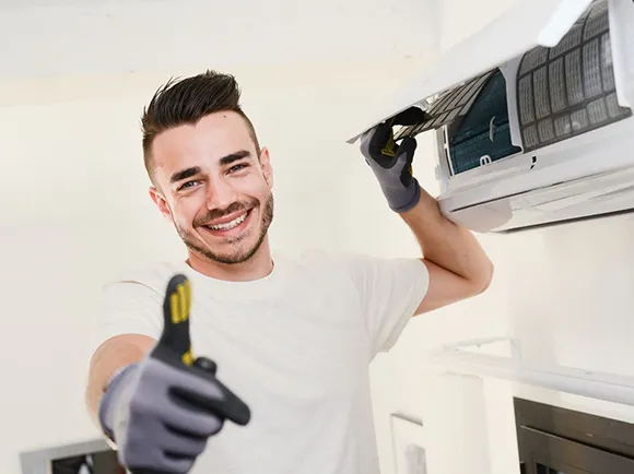 A technician in a uniform working on a split system AC unit, showcasing expert repair services.