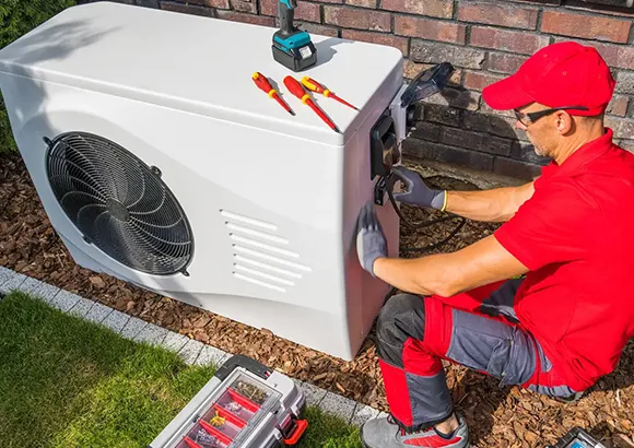Technician in red uniform working on a cooling system repair.